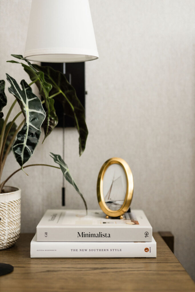 Minimal nightstand with decor, books, plant and light.